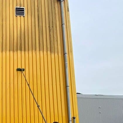 Bardage métallique jaune terni par les salissures et traces de ruissellement